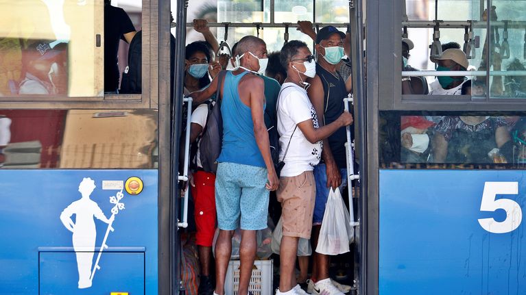 Kasvomaskeihin pukeutuneita matkustajia bussin kyydissä.