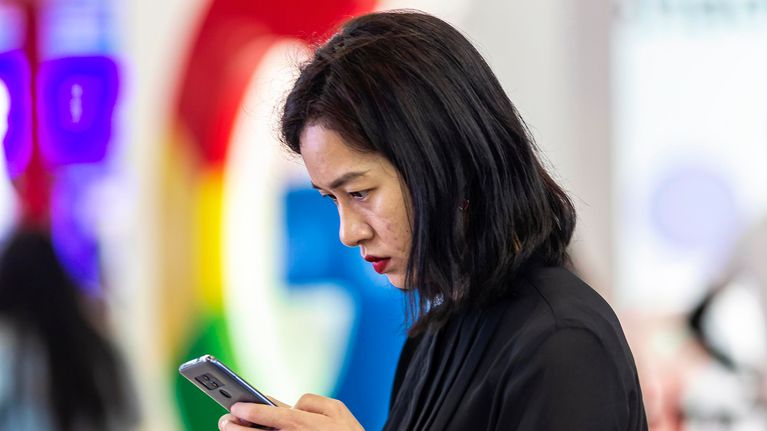 Nainen selaa puhelinta Googlen logon edustalla messuilla Guiyangissa Kiinassa