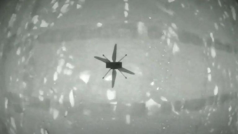 Mustavalkoinen kuva pienen helikopterin varjosta kaarevalla pinnalla. 
