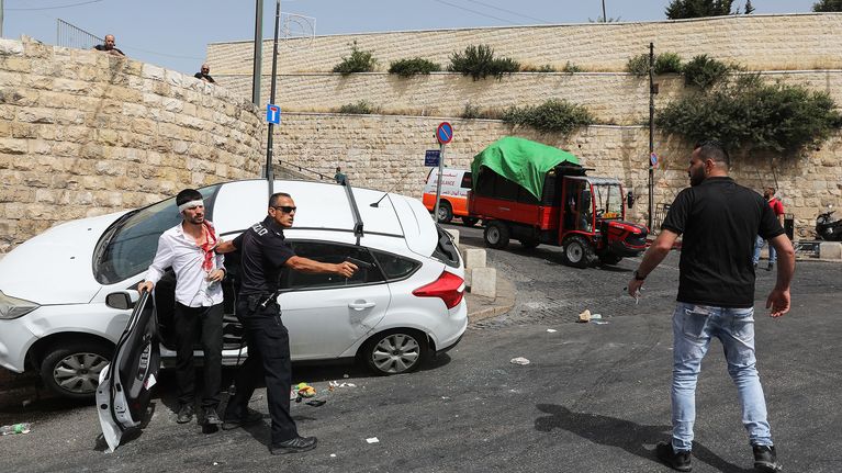 Israelilaine npoliisi osoittaa aseella palestiinalaismiestä.