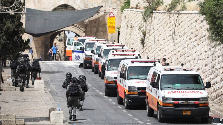 Aseistautuneet israelilaispoliisit kävelivät 10.toukokuuta palestiinalaisambulanssien ohi Temppelivuorella Jerusalemissa.