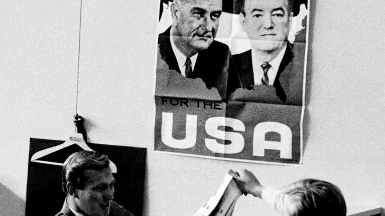  Uutistoimituksen työtiloja. Maisemakonttori vuodelta 1965. Sermein toisistaan erotettuja työtiloja. Seinällä USA-juliste.
