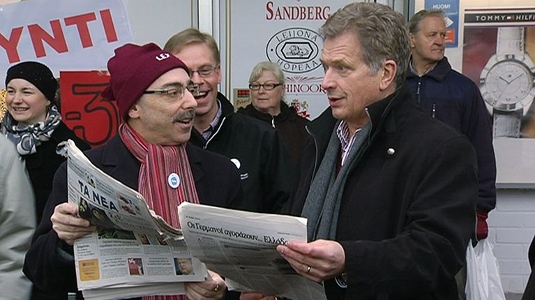 Sauli Niinistö ja Ben Zyskowicz selailevat kreikkalaisia sanomalehtiä kampanjatilaisuudessa.