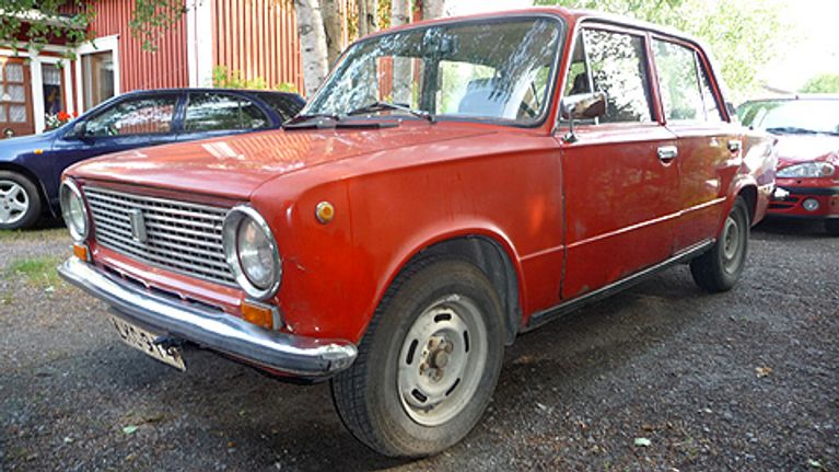 Kuvassa punainen lada sivusta kuvattuna.