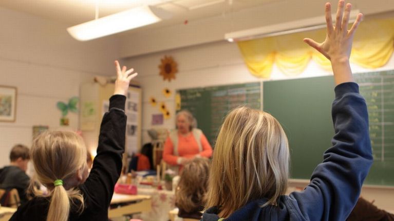 Oppilaat viittaavat luokassa. 
