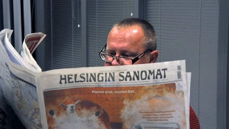 Mies lukee sanomalehteä.