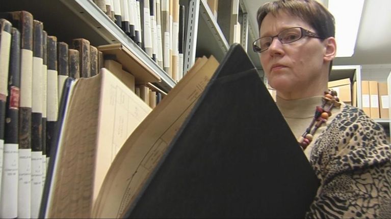 Tuija Korhonen katsoo arkistossa kirkonkirjaa