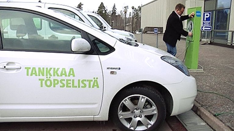 Mies lataa sähköauton akkuja.