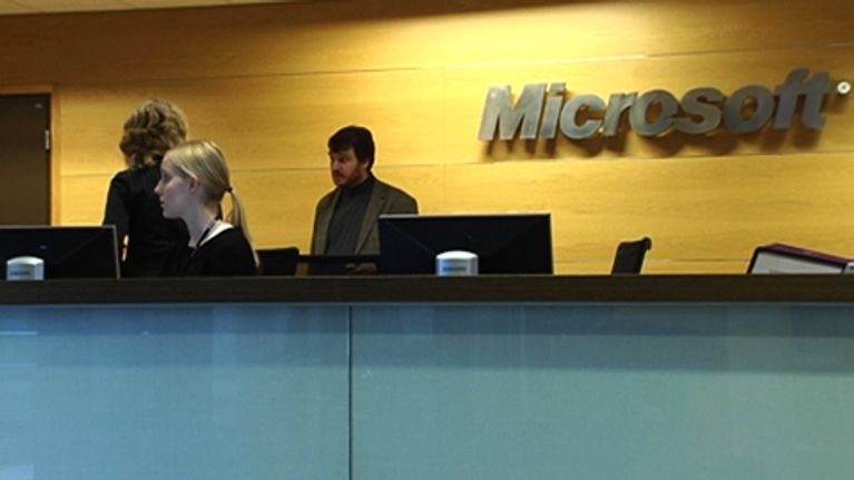 microsoftin konttori, työntekijöitä, yhtiön logo taustalla