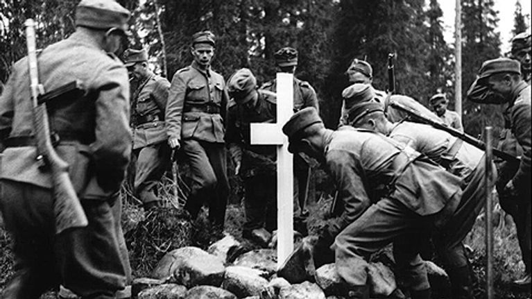 Suomalaiset sotilaat pystyttävät muistomerkkiä partisaanien uhreille.