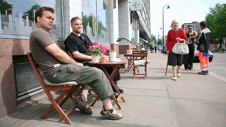 Miehet kahvikupin ääressä katukahvilassa