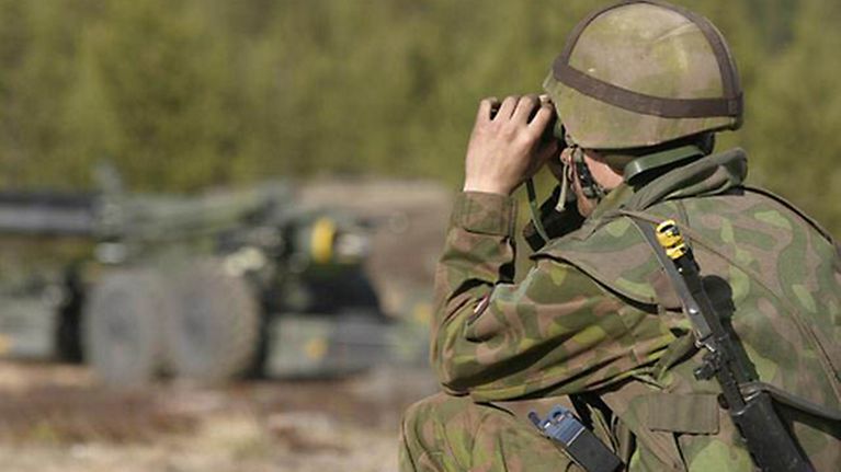Suomalaisen armeijan varusmies rynnäkkökivääri olallaan.