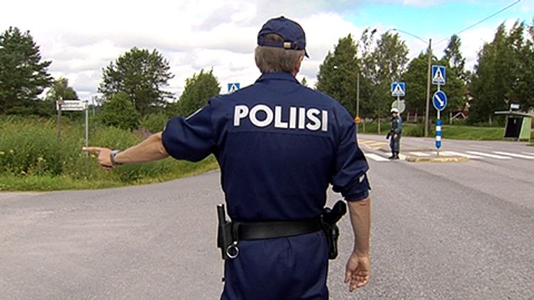 Poliisi pysäyttää henkilöautoa maantiellä.