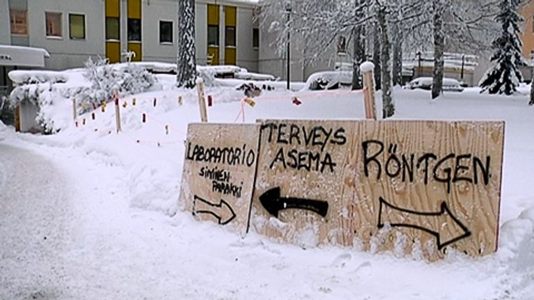 Tilapäiset vanerilevylle piirretyt opastekyltit Porvoon Näsin terveyskeskuksen edustalla.
