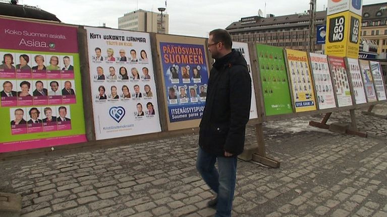 Mies katselee vaalimainoksia torilla.