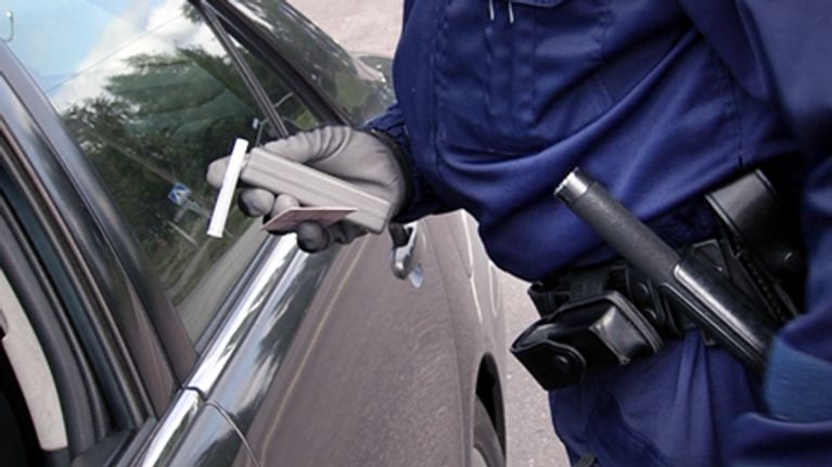 Poliisi tutkii alkometria auton  vieressä.