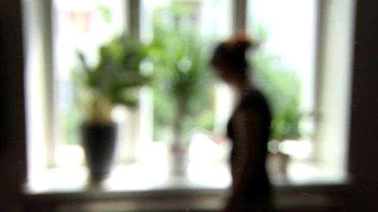 Naisen silhuetti ikkunaa vasten