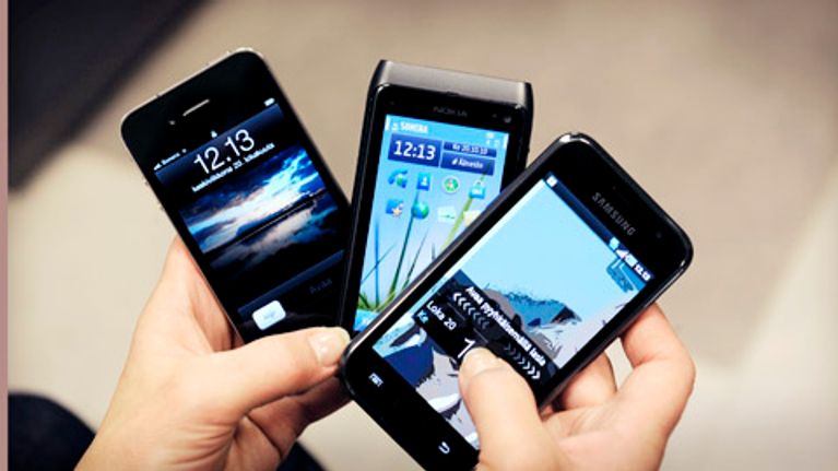 Älypuhelimet iPhone, Nokia ja Samsung viuhkana kädessä.