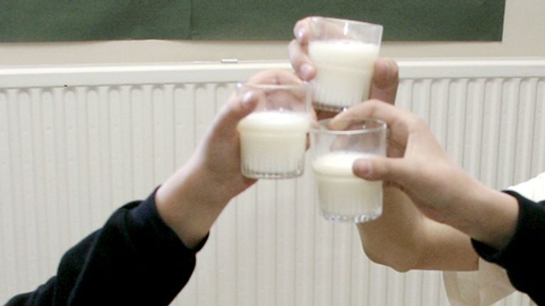 Lapset kilistelevät maitolaseilla.