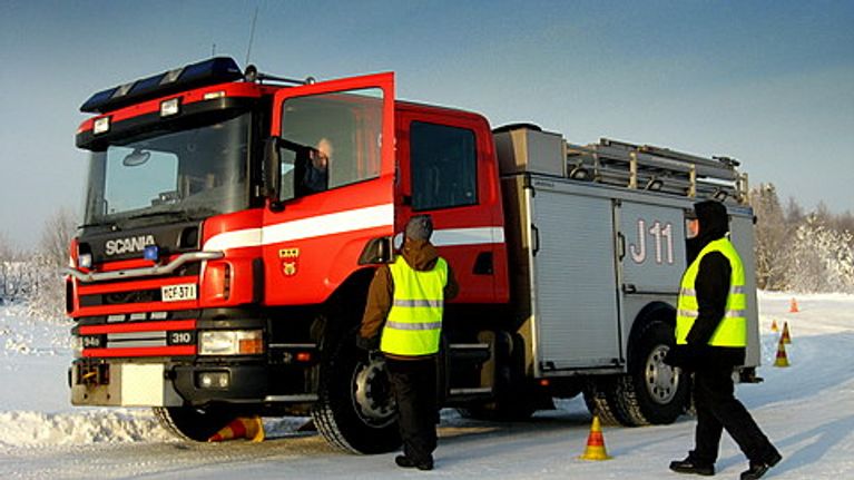 paloauto ja kaksi miestä heijastinliiveissä