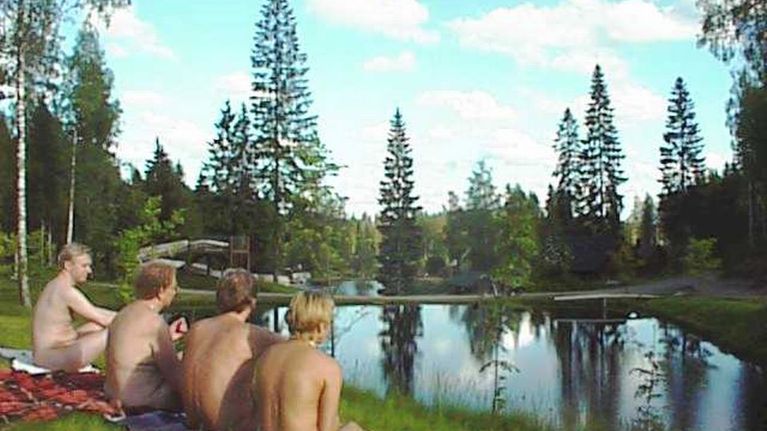 Neljä alastonta ihmistä istuu ruohikolla.