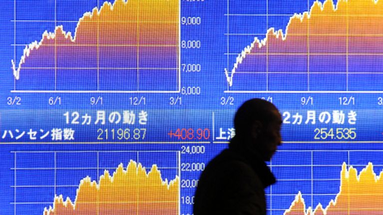 Liikemies kävelee Nikkei-ideksitaulun ohi Tokion pörssissä.