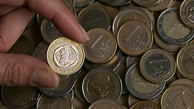 Henkilö pitelee kreikkalaista eurokolikkoa