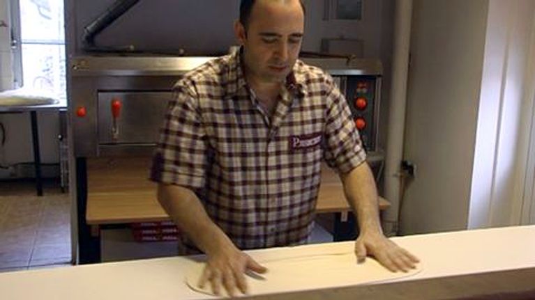 Ravintoloitsija Erkan Uzun pyöräyttää pizzapohjan