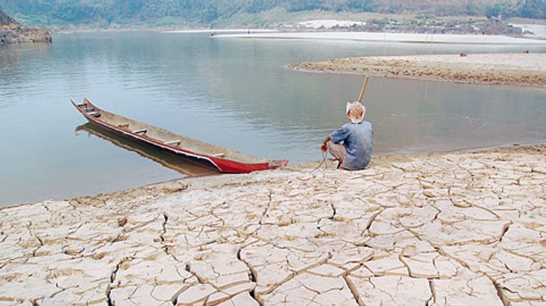 Thaimaalainen mies istuu pahoin kuivuneen Mekong-joen rannalla. 