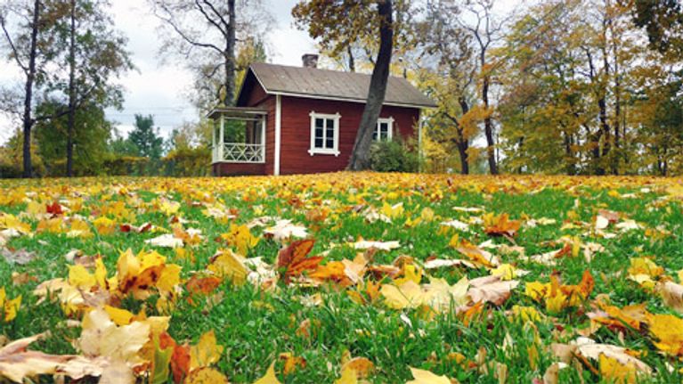 Punainen mökki syksyisessä maisemassa.