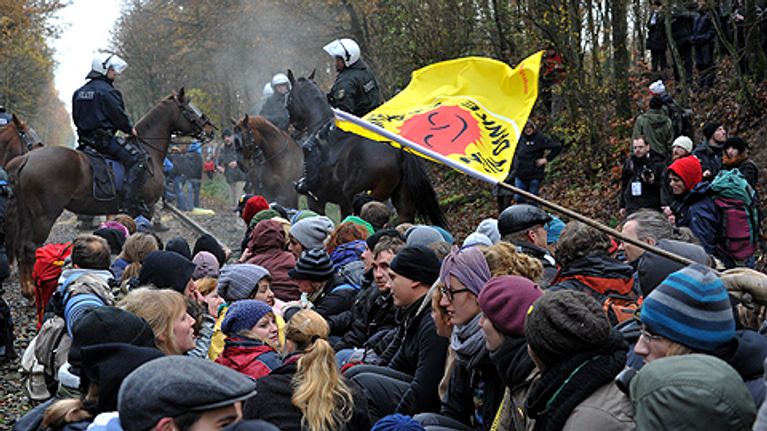 Mielenosoittajat istuvat raiteilla.