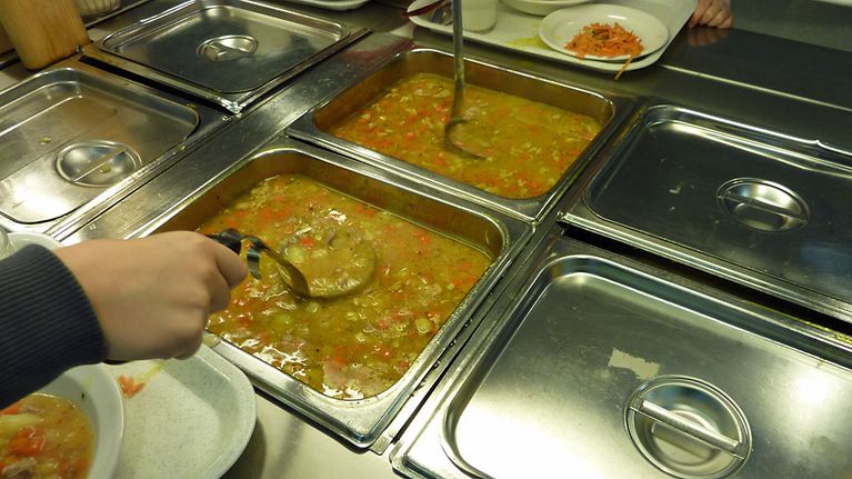 Koululainen ottaa kauhalla kalkkunakeittoa kouluruokalan linjastolta.