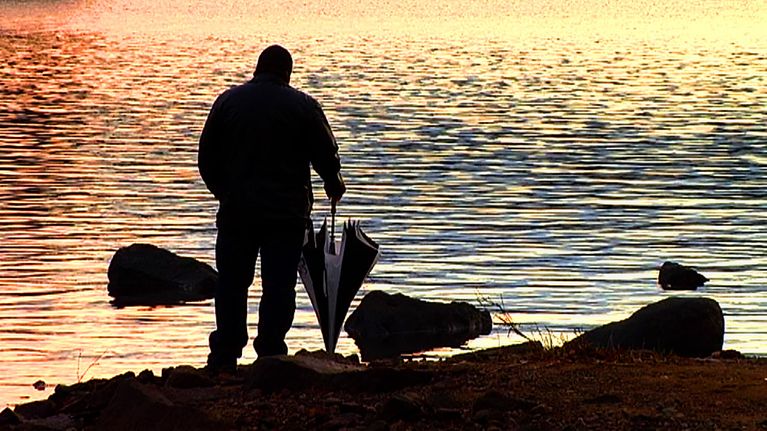 Mies rannalla auringonlaskussa.