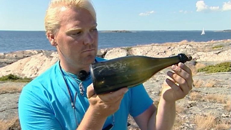 Christian Ekström esittelee yhtä löytyneistä samppanjapulloista.
