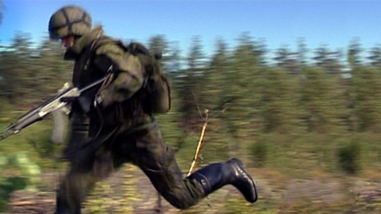 Sotilas juoksee metsässä kiväärin kanssa