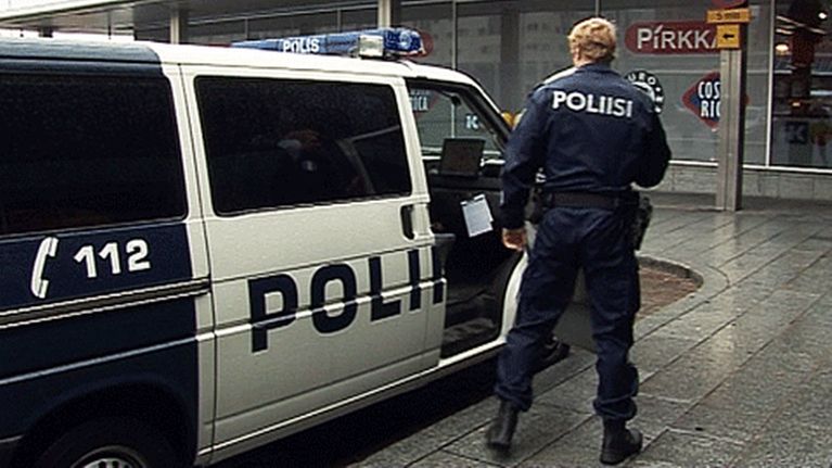 Poliisi nousee poliisiautosta.