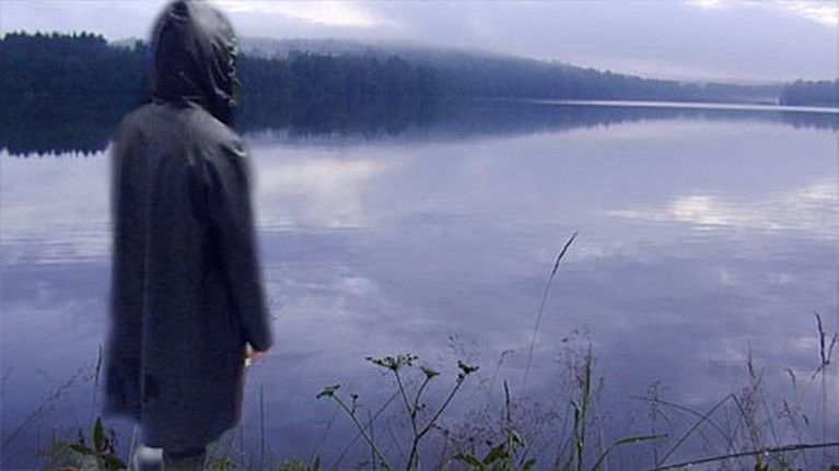 Hahmo seisoo järven rannalla.