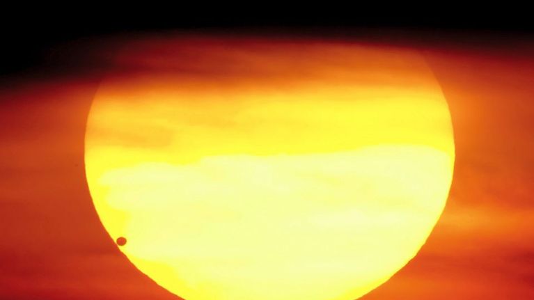 Venus tummana pallona auringon alareunassa.