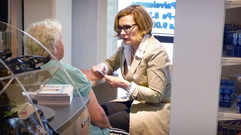 Ministeri Paula Risikko keskustelee apteekin asiakkaan kanssa.
