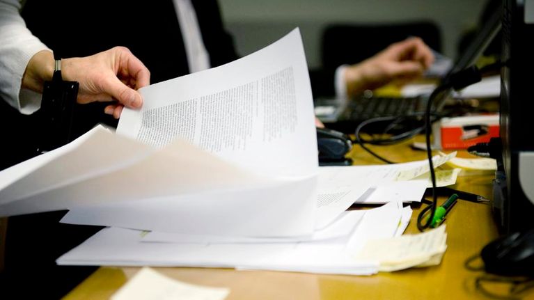 Työntekijä selaa paperipinoa.
