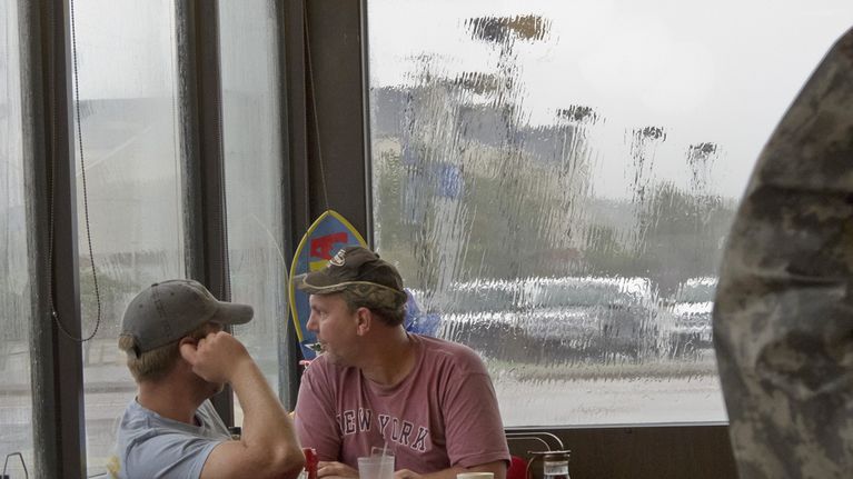 Miehet pitävät sadetta kahvilassa