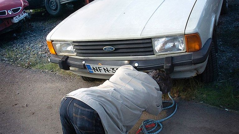 Mies kiinnittää hinausköyttä autoon.
