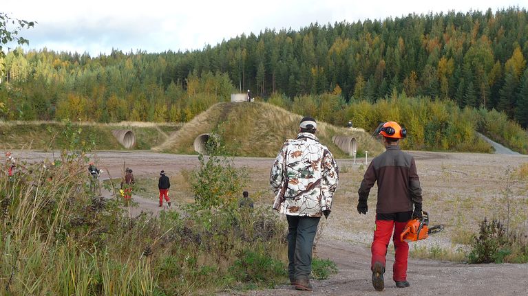 Talkoolaiset kävelevät kohti maataideteosta