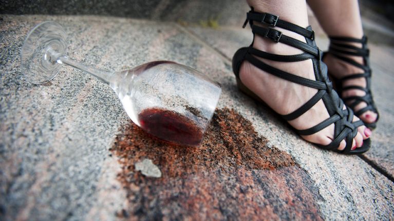 Viinilasi kaatuneena naisen jalkojen juuressa.