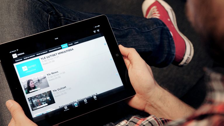 Mies katsoo iPadilla  Uutiset-sivustoa Ylen Areenasta.
