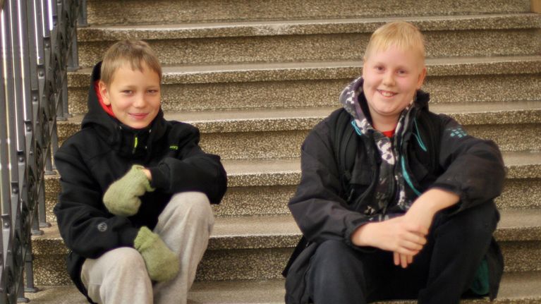 Kaksi poikaa istuu rappusilla