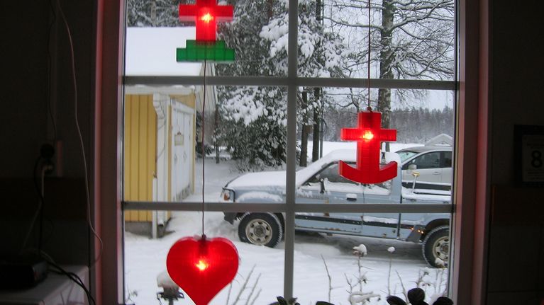 Anneli Lehtosen ikkunassa roikkuvat punaiset jouluvalot joissa risti, sydän ja ankkuri