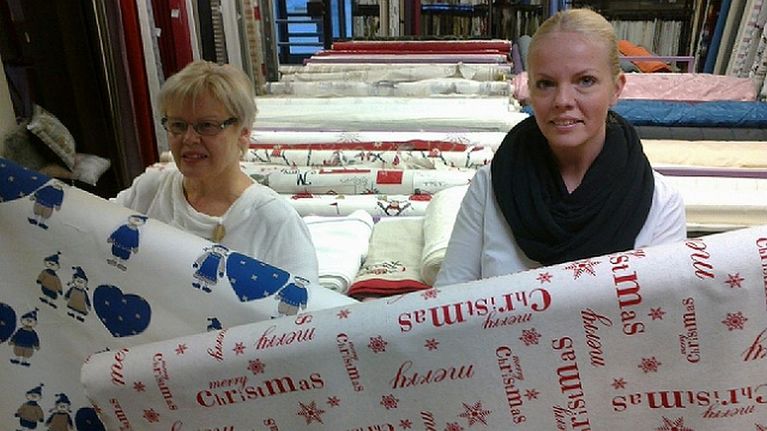 Mode Kankaan aiempi omistaja Aulikki Livisti esittelee muutaman vuoden takaista joulukangasmuotia, uusi yrittäjä Pauliina Marshall pitelee tämän joulun uutuuskangasta. 