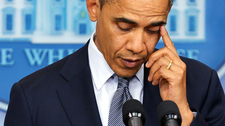 Barack Obama pyyhkii kyyneleitä puhujankorokkeella.
