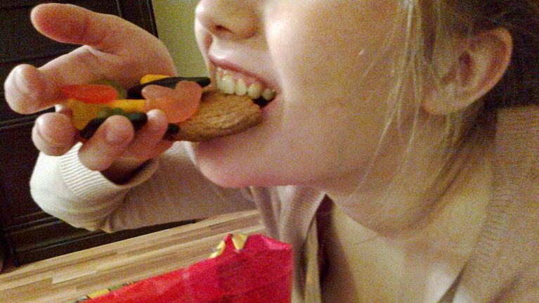 Nainen kahmii karkkia ja keksiä suuhunsa 
